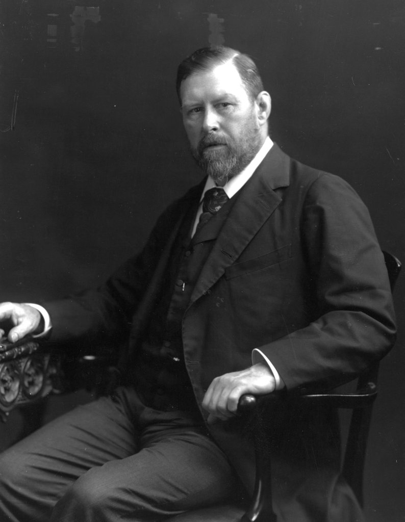 Black and white photo of Bram Stoker sitting in a chair and looking at the camera.